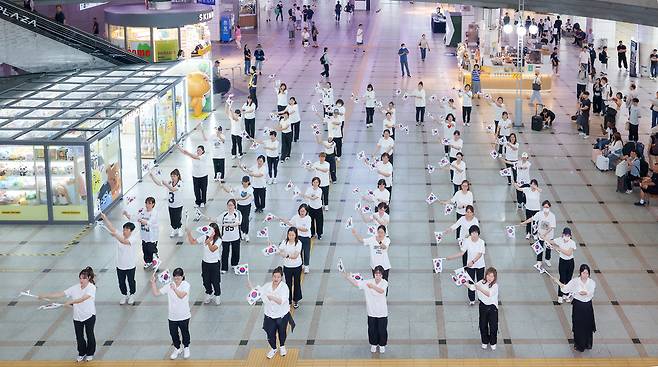 ▲ 제80주년 광복절을 나흘 앞둔 11일 오후 수원시 팔달구 수원역 대합실에서 열린 '광복, 그날의 기쁨 재현하다' 행사에서 권선구 주민자치 댄스 프로그램 수강생들이 태극기를 들고 플래시몹 공연을 하고 있다./전광현 기자 maggie@incheonilbo.com