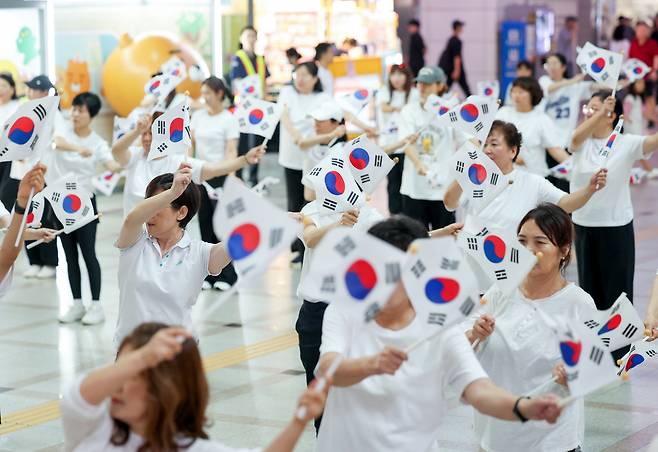 ▲ 제80주년 광복절을 나흘 앞둔 11일 오후 수원시 팔달구 수원역 대합실에서 열린 '광복, 그날의 기쁨 재현하다' 행사에서 권선구 주민자치 댄스 프로그램 수강생들이 태극기를 들고 플래시몹 공연을 하고 있다./전광현 기자 maggie@incheonilbo.com