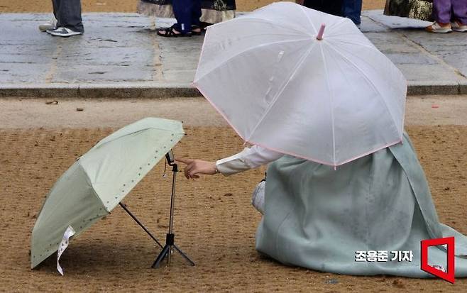비 내리는날, 경복궁을 찾은 한 외국인 관광객이 소중한 휴대폰이 젖을새라 셀카 한장을 찍기 위해서 휴대폰 위에 우산을 씌우는 모습이 정감 있다. 조용준 기자