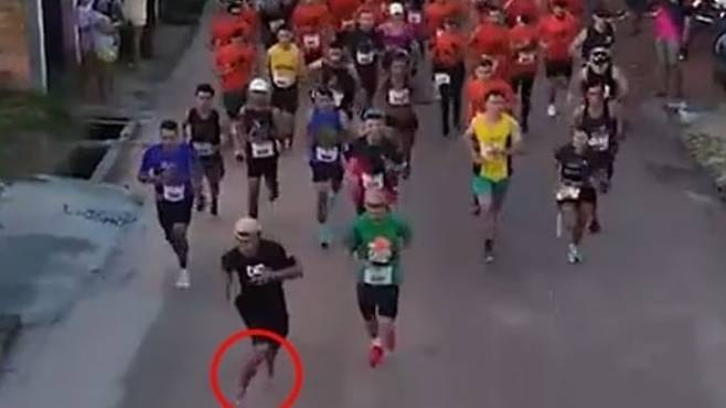 이사크 피뉴가 슬리퍼만 신은 채 마라톤 대회에 난입해 선두에서 달리고 있는 모습. /데일리메일