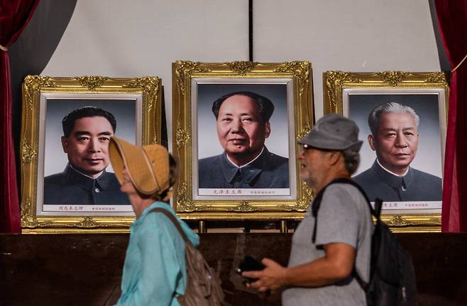 2025년 8월 중국 베이징 왕푸징 거리에 전시된 저우언라이, 마오쩌둥, 류샤오치의 초상화 앞을 지나가는 사람들. /연합뉴스