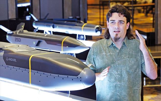 < ‘트레이드 마크’ 하와이안 셔츠 입고 회사소개 > 파머 러키 안두릴인더스트리즈 창립자가 지난 7일 서울 당주동 포시즌스호텔에서 열린 안두릴코리아 설립 행사에서 자사 무기 제품과 꽃무늬가 그려진 하와이안 셔츠를 입고 회사를 소개하고 있다. 러키 창립자는 자동차 판매원인 부친의 하와이안 셔츠를 물려받아 입던 유년시절 습관을 지금까지 이어왔고, 어느새 이 옷은 그의 ‘트레이드 마크’가 됐다. 그의 옆에 안두릴이 개발한 미사일 ‘바라쿠다’ 모형이 있다. 자율항공체(AAV)로 기존 무기보다 부품 수를 크게 줄여 빠른 생산이 가능하도록 설계된 것이 특징이다.   김범준 기자