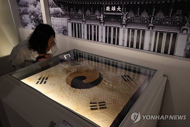 '서울 진관사 태극기' (서울=연합뉴스) 강민지 기자 = 11일 서울 중구 덕수궁 돈덕전에서 열린 특별전 '빛을 담은 항일유산' 언론공개회에서 관계자가 서울 진관사 태극기를 살펴보고 있다.  2025.8.11 mjkang@yna.co.kr