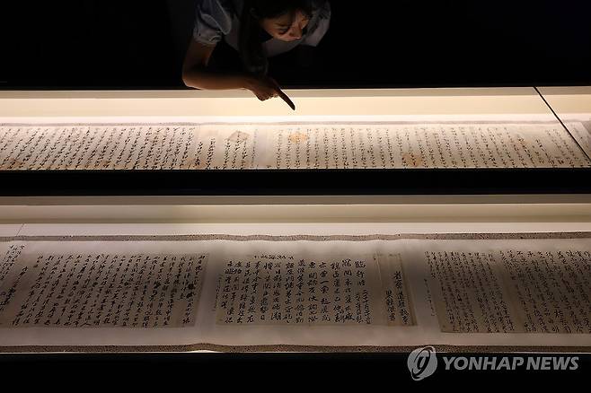항일의병 문서 (서울=연합뉴스) 강민지 기자 = 11일 서울 중구 덕수궁 돈덕전에서 열린 특별전 '빛을 담은 항일유산' 언론공개회에서 관계자가 항일의병 관련 문서를 살펴보고 있다.  2025.8.11 mjkang@yna.co.kr
