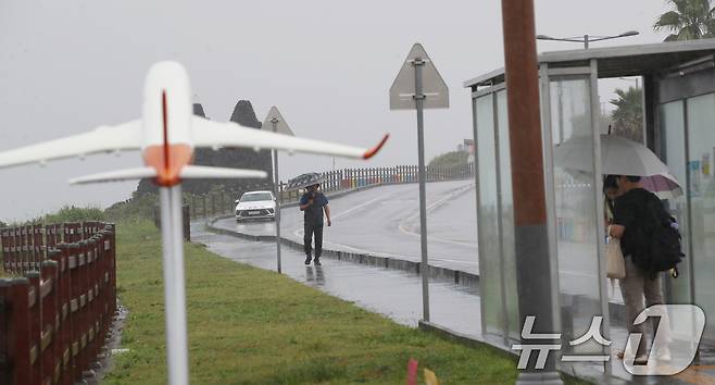 제주에 비가 내리면서 폭염특보가 모두 해제된 11일 오전 제주시 용담해안도로에서 우산을 쓴 관광객들이 발걸음을 옮기고 있다. 2025.8.11/뉴스1 ⓒ News1 오현지 기자