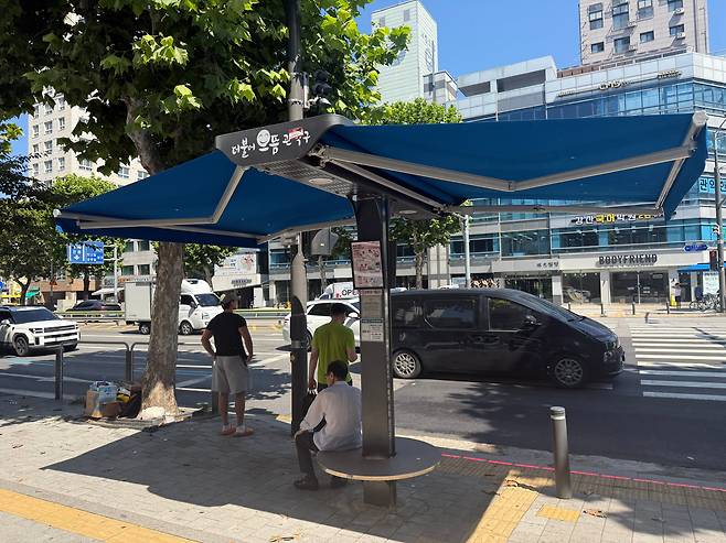 12일 서울 관악구 봉천역 인근 한 횡단보도 앞 스마트 그늘막에서 사람들이 휴식을 취하고 있다. /이호준 기자