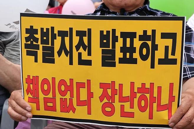 경북 포항지진 정신적 손해배상 소송의 항소심 패소 판결과 관련해 포항지진 범시민대책본부가 지난 6월13일 포항 육거리 인근 중앙상가에서 개최한 시민궐기대회에서 시민들이 항의 손팻말을 들고 있다. 연합뉴스