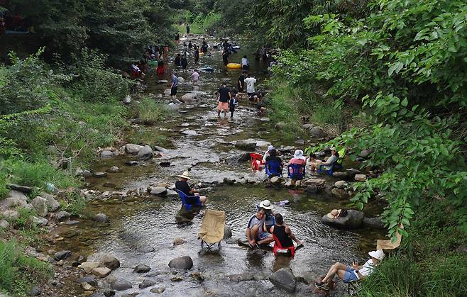 중미산에서 흘러내린 물이 지나는 신복천에서 시민들이 물속에 놓아둔 의자에 앉아 쉬고 있다.