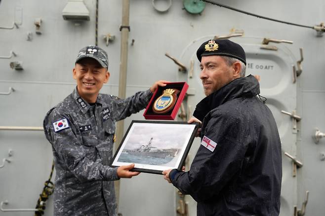 리치몬드함 함장 리처드 캠프 중령(오른쪽)이 리치몬드함 플라크와 영국 출항 당시 촬영한 사진을 광명함장 배준희 중령에게 전달하고 있다/사진=주한영국대사관