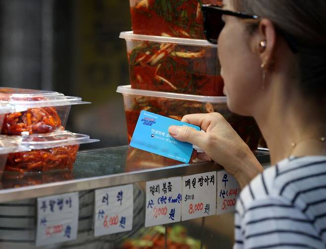 서울 시내의 한 전통시장에서 한 시민이 민생회복 소비쿠폰을 이용해 반찬을 구매하고 있다. [사진 | 뉴시스]