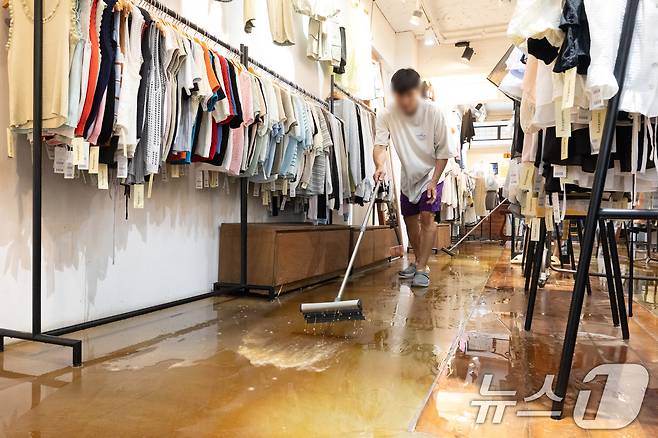 13일 오후 서울 은평구 연신내역 인근 옷가게에 폭우로 물이 넘쳐와 상인이 가게를 청소하고 있다. 2025.8.13/뉴스1 ⓒ News1 이승배 기자