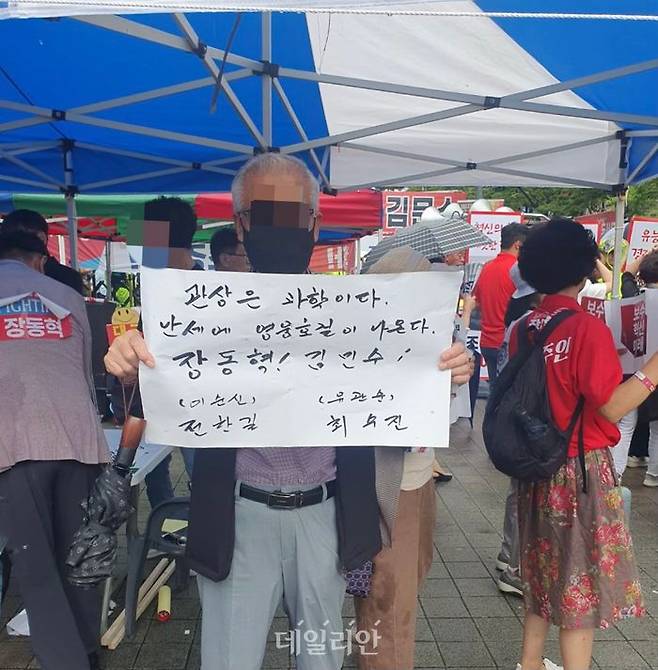 부산 시민 조모(70대·남)씨가 12일 부산 벡스코 열린 '국민의힘 8·22 전당대회 부산·울산·경남 합동연설회' 행사장 앞에서 전한길 씨는 이순신 장군, 최수진 최고위원 후보는 유관순 열사에 비유한 문구를 적은 팻말을 활짝 들어 보이고 있다. ⓒ데일리안 김민석 기자
