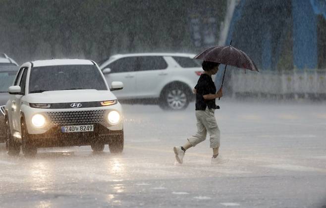 우산을 쓴 시민이 조심스럽게 길을 건너고 있다. 뉴스1