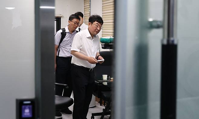 유튜브 채널 ‘신의한수’ 운영자 신혜식 대표가 13일 서울 마포구 사무실에서 윤석열 정부 시절 대통령실의 민간인 시위대 동원 의혹과 관련해 서울경찰청 안보수사과 수사관들에게 휴대전화를 임의제출 하고 있다. 연합뉴스