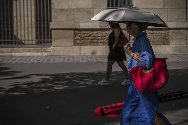 [파리=AP/뉴시스] 12일(현지 시간) 프랑스 파리에서 시민이 양산을 쓴 채 이동하고 있다. 2025.08.13.