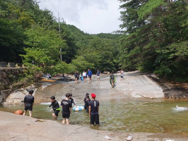 야트막한 웅덩이를 만든 계곡에서 피서객들이 물놀이를 하며 즐거운 한때를 보내고 있다.
