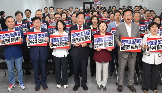 국민의힘 송언석 비상대책위원장 겸 원내대표를 비롯한 당 관계자들이 14일 서울 여의도 중앙당사에서 열린 긴급의원총회에서 전날 김건희 특검의 당사 압수수색과 관련한 규탄 구호를 외치고 있다. [연합뉴스]