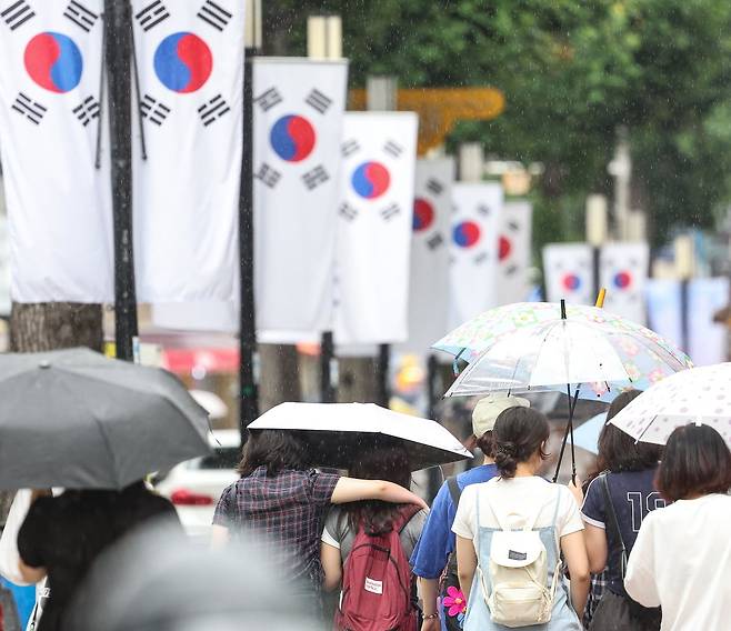 대구 중구 동성로에 광복절을 앞두고 태극기가 게양된 가운데 시민들이 우산을 쓰고 이동하고 있다. 사진=연합뉴스