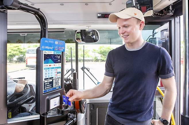외국인 관광객이 제주 시내버스에서 비자 카드를 탭하여 승차하고 있다. 비자가 이달 13일 제주도에 도입한 개방형 교통결제 시스템(Open-loop Transit)으로 교통카드를 새로 구매하거나 충전할 필요 없이 외국인이 자국에서 사용하던 비자 카드로 버스를 이용할 수 있게 됐다. 비자코리아 제공