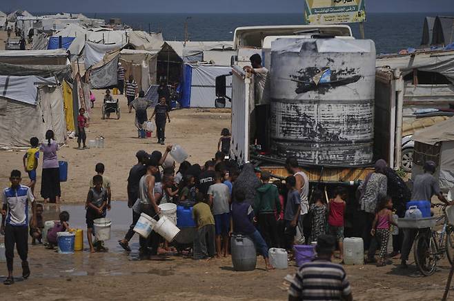 [칸유니스=AP/뉴시스] 13일(현지 시간) 가자지구 칸유니스 난민촌에서 폭염 속 팔레스타인 피란민들이 급수 차량에서 물을 받고 있다. 이스라엘이 가자 주민 이주를 위해 인도네시아, 남수단 등 5개국과 접촉 중인 것으로 알려졌다. 2025.08.14.