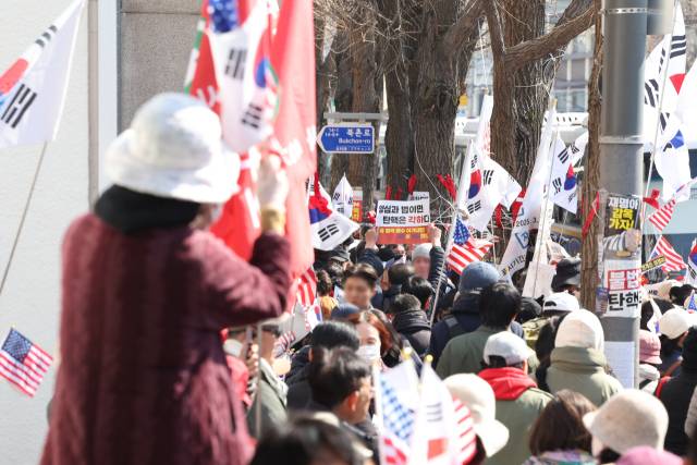 ▲윤석열 대통령 탄핵심판 사건이 헌법재판소에 접수된 지 95일째인 19일 서울 종로구 헌재 건너편에서 윤 대통령 지지자가 탄핵 각하를 촉구하는 가운데 보행자와 대통령 지지자가 뒤섞여 있다. ⓒ연합뉴스