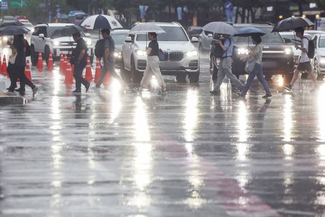 장맛비가 내린 13일 서울 종로구 광화문네거리에서 우산을 쓴 시민들이 출근길 발걸음을 재촉하고 있다. 뉴스1