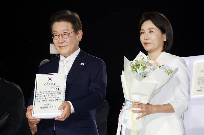 국민임명장 받은 이재명 대통령이재명 대통령과 김혜경 여사가 15일 서울 광화문광장에서 열린 제21대 대통령 국민임명식 행사에서 임명장을 들어 보이고 있다. /연합뉴스