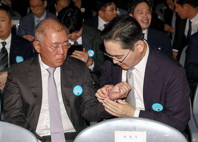 15일 서울 세종대로 광화문광장에서 열린 제21대 대통령 국민임명식 ‘광복 80년, 국민주권으로 미래를 세우다’ 행사에서 이재용 삼성전자 회장이 정의선 현대차그룹 회장에게 팔찌를 채워주고 있다 (사진=연합뉴스)