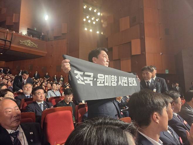 안철수 국민의힘 당대표 후보가 15일 제80주년 광복절 경축식에 참석해 축사 중인 이재명 대통령을 향해 항의 메시지를 전달하는 모습 (안철수 캠프 제공)