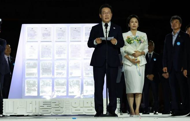 이재명 대통령과 김혜경 여사가 15일 서울 세종대로 광화문광장에서 열린 제21대 대통령 국민임명식 '광복 80년, 국민주권으로 미래를 세우다' 행사에서 국민 대표 80인으로부터 '빛의 임명장'을 받은 뒤 감사 인사를 하고 있다. 연합뉴스