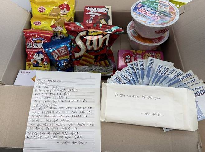 부산 덕천지구대 앞에 놓여있던 1000원권 지폐 30장과 과자꾸러미. 부산 북구 제공