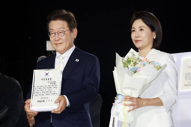 이재명 대통령과 김혜경 여사가 15일 서울 광화문광장에서 열린 제21대 대통령 국민임명식 행사에서 임명장을 들어 보이고 있다. 대통령실통신사진기자단