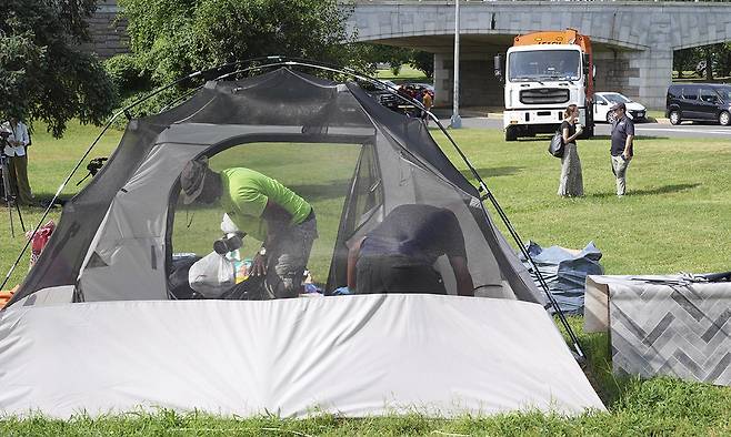 14일(현지시간) 트럼프 대통령의 방침에 따라 워싱턴에서 노숙자 텐트촌 철거 작업이 시작되면서 노숙자들이 자신의 소지품을 텐트에서 꺼내고 있다. 워싱턴=AP연합뉴스