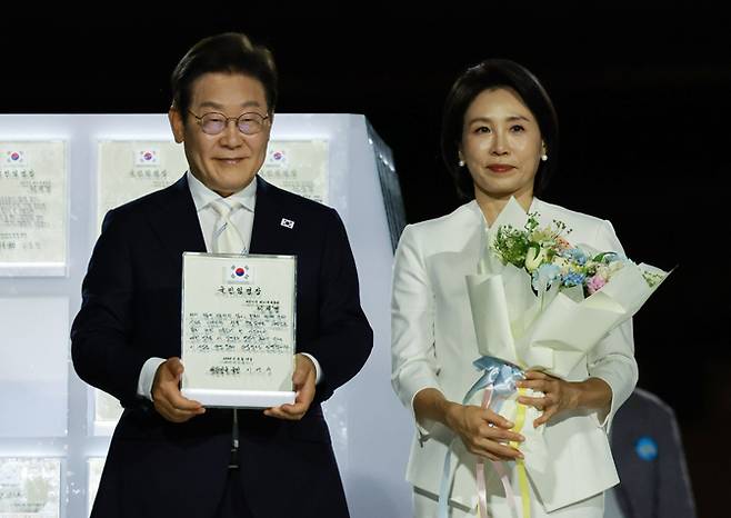 이재명 대통령과 김혜경 여사가 15일 서울 세종대로 광화문광장에서 열린 제21대 대통령 국민임명식 '광복 80년, 국민주권으로 미래를 세우다' 행사에서 국민 대표 80인으로부터 '빛의 임명장'을 받은 뒤 감사 인사를 하고 있다. 연합뉴스