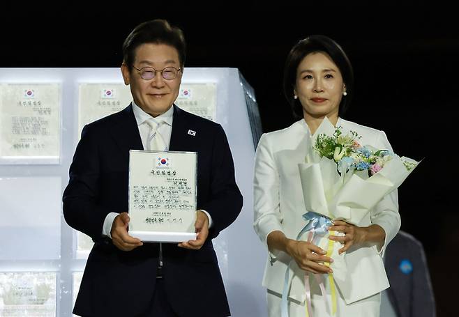 이재명 대통령과 김혜경 여사가 15일 서울 세종대로 광화문광장에서 열린 제21대 대통령 국민임명식 '광복 80년, 국민주권으로 미래를 세우다' 행사에서 국민 대표 80인으로부터 '빛의 임명장'을 받은 뒤 감사 인사를 하고 있다. 연합뉴스