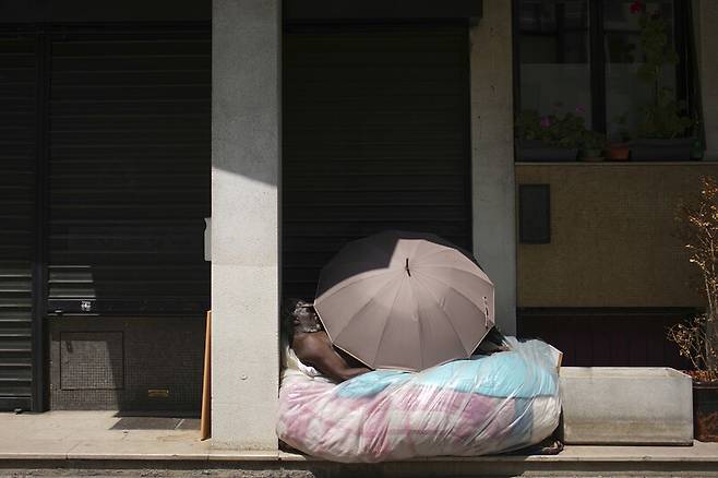 지난 7월, 프랑스 파리에서 한 노숙인이 폭염 속에 우산으로 그늘을 만든 채 잠을 청하고 있다. AP연합