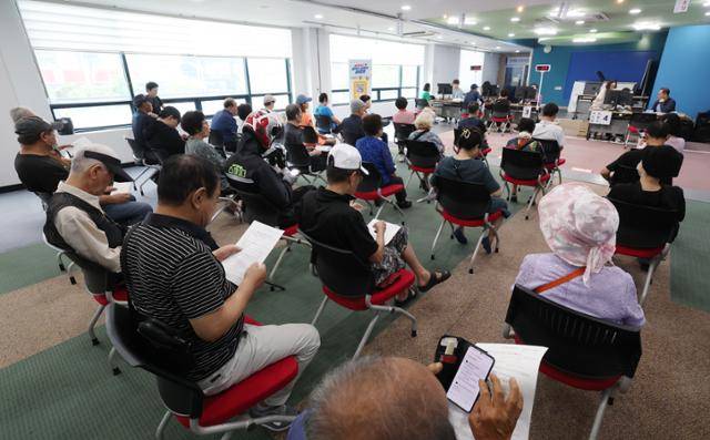 민생회복 소비쿠폰의 1차 신청 첫날인 지난달 21일 경기 수원시 팔달구 인계동행정복지센터에서 시민들이 신청서를 작성한 뒤 대기하고 있다. 뉴스1