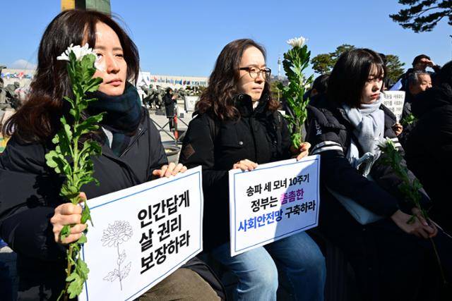지난해 2월 26일 용산 대통령 집무실 앞에서 '송파 세 모녀 10주기 추모제'에 참여한 시민들이 피켓을 들고 고인들을 추모하고 있다. 박시몬 기자