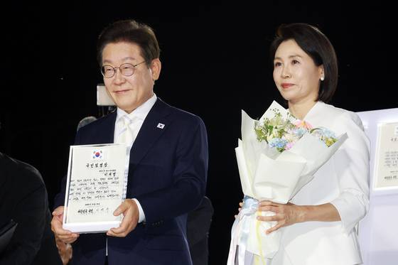 이재명 대통령과 김혜경 여사가 15일 서울 광화문광장에서 열린 제21대 대통령 국민임명식 행사에서 임명장을 들어 보이고 있다. 연합뉴스