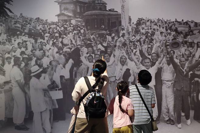 광복 80주년을 하루 앞둔 14일 서울 종로구 서울역사박물관을 찾은 한 가족이 ‘우리들의 광복절’ 특별전을 관람하고 있다. 전시된 사진은 광복 다음 날인 1945년 8월 16일 오전 서울 서대문구 서대문형무소에서 석방된 독립운동가들이 군중과 함께 만세를 외치고 있는 장면이다. 한수빈 기자