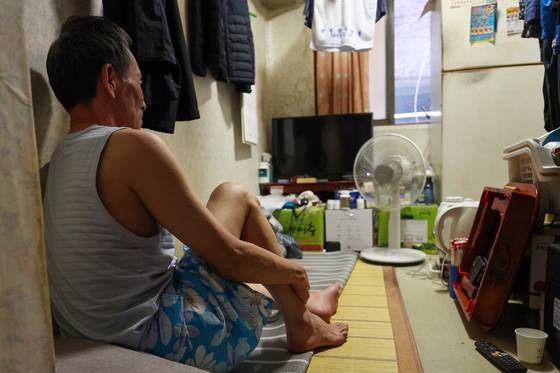 A man sits in a jjokbang, a type of substandard housing in Korea that consists of micro-unit rooms with shared bathrooms. [YONHAP]