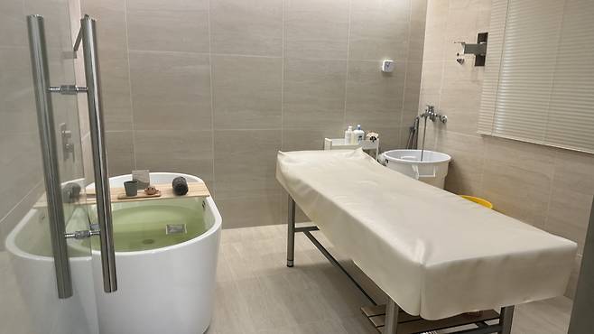 A bathtub is prepared with a mugwort bath bomb, accompanied by tea and a rubber mat for the scrub in one of the private rooms at seshin shop Damda. [WOO JI-WON]