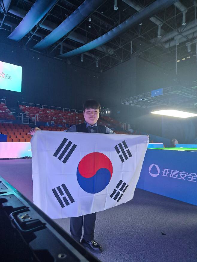 세계캐롬연맹(UMB) 3쿠션 세계 랭킹 1위인 조명우가 14일 중국 청두 중국민영항공대학교 체육관에서 열린 2025 제12회 청두월드게임 남자 캐롬 3쿠션 결승에서 이집트의 사메 시돔을 누르고 우승을 차지한 뒤 태극기를 들고 포즈를 취하고 있다. 대한당구연맹