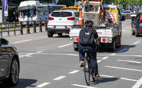 남구 경성대·부경대 역 차량들 사이로 한 학생이 자전거를 타고 이동하고 있다. 이원준 기자