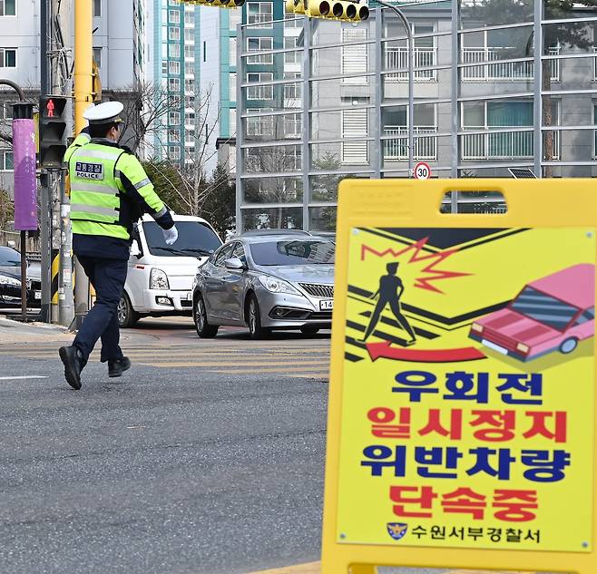A traffic officer conducts checks for vehicles failing to make a full stop before turning right at an intersection in Suwon, Gyeonggi Province, in March. The Gyeonggi Nambu Provincial Police plan multiple enforcement campaigns this year to strengthen compliance with the rule and reduce pedestrian accidents. (Newsis)