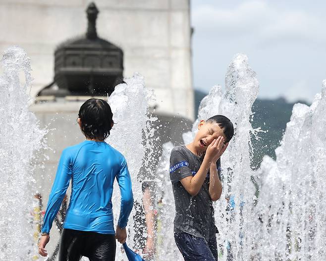 Children play in the fountain installed at Gwanghwamun Square in Jongno-gu, central Seoul on Sunday, as a heat wave advisory was issued in the capital city that day. (Yonhap)