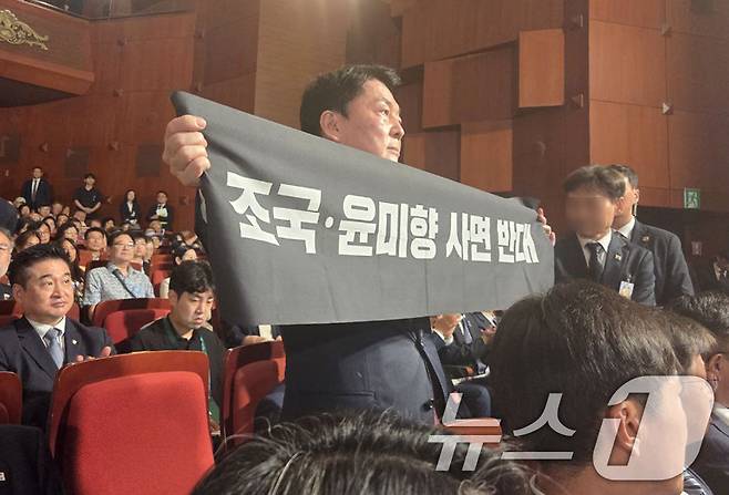 안철수 국민의힘 당대표 후보가 15일 오전 서울 종로구 세종문화회관에서 열린 제80주년 광복절 경축식에 참석해 경축사 중인 이재명 대통령을 향해 조국 전 조국혁신당 대표와 윤미향 전 의원의 사면 반대 플래카드를 들어보이며 항의하고 있다. (안철수 캠프 제공) 2025.8.15/뉴스1