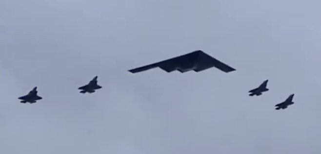 미국의 B-2 스텔스 폭격기(가운데)와 F-35 전투기 4대로 구성된 비행 편대가 15일(현지 시간) 미-러 정상회담이 열린 알래스카주 앵커리지의 군사 기지 상공을 비행하고 있다. 사진 출처 ‘X’