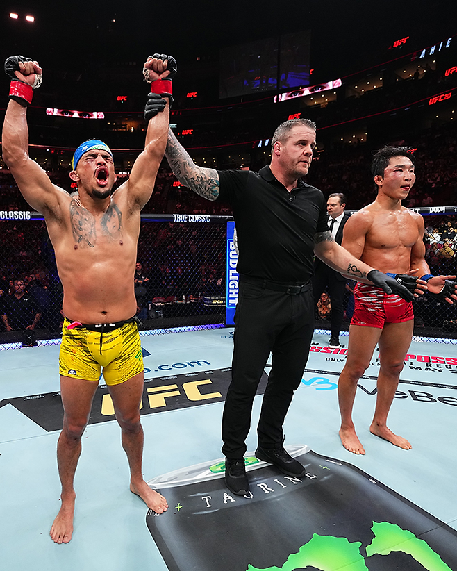 다니에우 구스타부 곤자가 산투스가 2025년 5월 캐나다 퀘벡주 몬트리올 벨 센터 UFC 315 제2경기 승리 선언을 받자 기뻐하고 있다. UFC 밴텀급 2승 1패 후 체급을 올려 이겼다. 오른쪽은 Road to UFC 시즌1 페더급 토너먼트 우승자 이정영. 사진=TKO