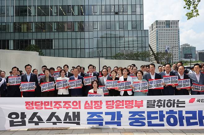 국민의힘의 송언석 비대위원장 겸 원내대표 등 의원들이 18일 김건희 여사 관련 의혹을 수사하는 민중기 특별검사팀 사무실이 마련된 서울 종로구 KT 광화문빌딩 웨스트 앞에서 현장 비상의원총회를 열고 야당탄압 정치보복 압수수색 규탄 손팻말을 들고 있다. [연합]